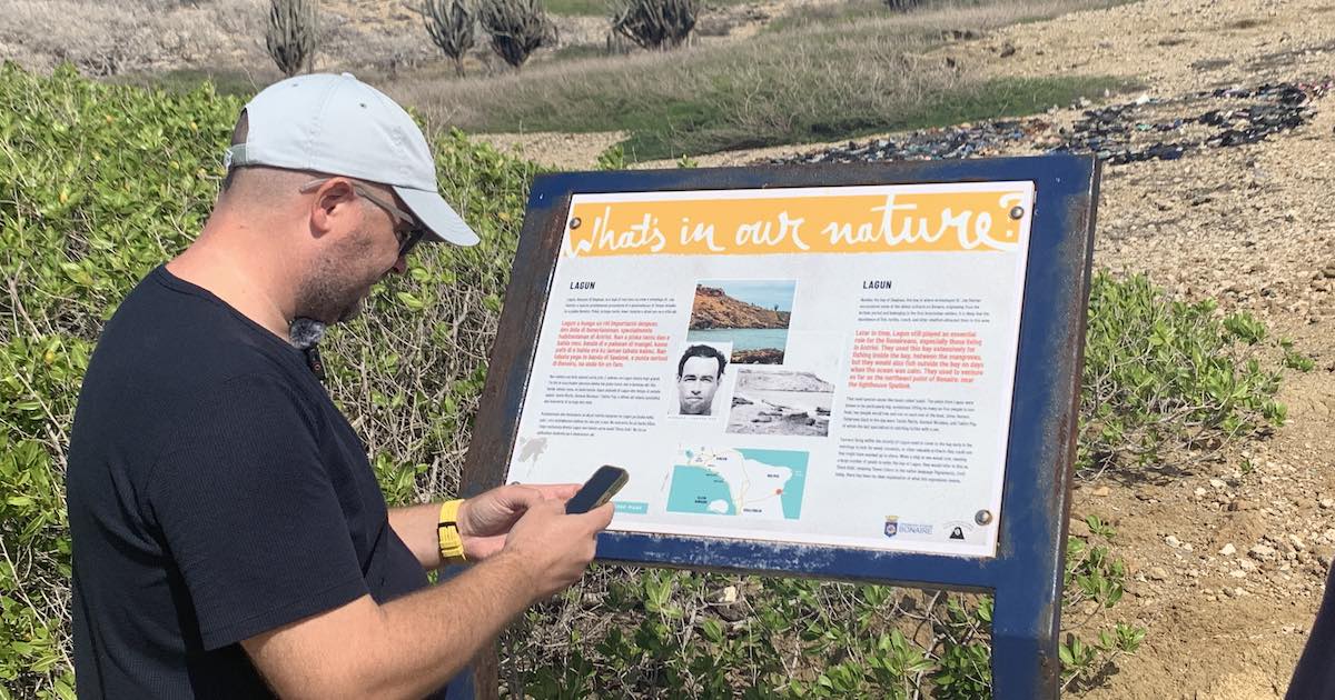 Jan Verbeek bij een bord bij de lagun met de slogan: 'It's in our nature'